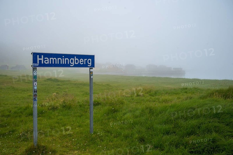 Town sign for Hamningberg on the Barents Sea in the midst of grassy landscape with fog and calm atmosphere, Hamningberg, Finnmark, Norway
