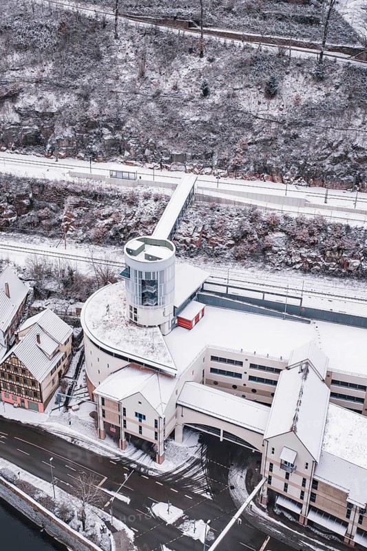 Modern building with snowy roof next to a snowy hill next to a river, Calw, Black Forest, Germany