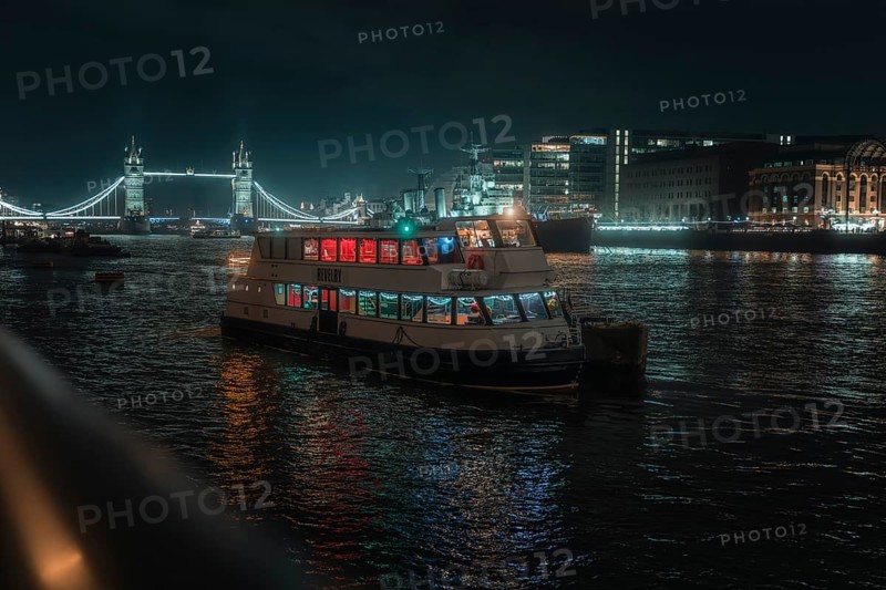 Illuminated boat on the Thames at night with Tower Bridge in the background, London, England, Great Britain