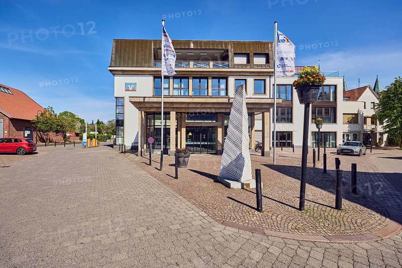 Volksbank Dammer Berge eG Hauptstelle Damme, general architecture, commercial building, modern building, advertising flags on flagpoles, barrier bollards, road made of paving stones and concrete paving stones, trees, blue sky, cirrus clouds, Mühlenstraße, dam, district of Vechta, Lower Saxony, Germany