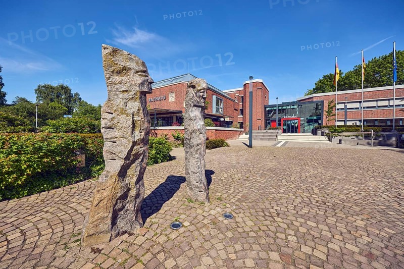 Town hall, stone sculpture, sculpture of people, brick building, modern architecture, lantern, flagpoles, flags, paving stone flooring, trees, shrubs, blue sky, cirrus clouds, Mühlenstraße, dam, Vechta district, Lower Saxony, Germany