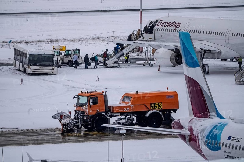 The onset of winter in North Rhine-Westphalia, flight operations are maintained at Düsseldorf airport with great effort, taxiways, passenger boarding, outdoor position, Eurowings, runway are freed from snow and ice with many clearing vehicles, airplanes are de-iced in front of takeoff, North Rhine-Westphalia, Germany