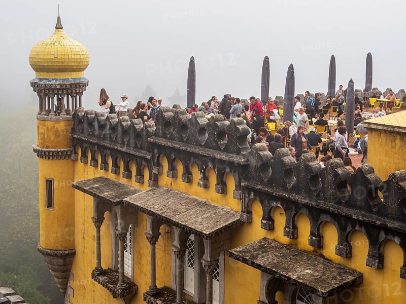 Tourists visiting the palace Palácio Nacional da Pena, foggy day, Sintra, Portugal