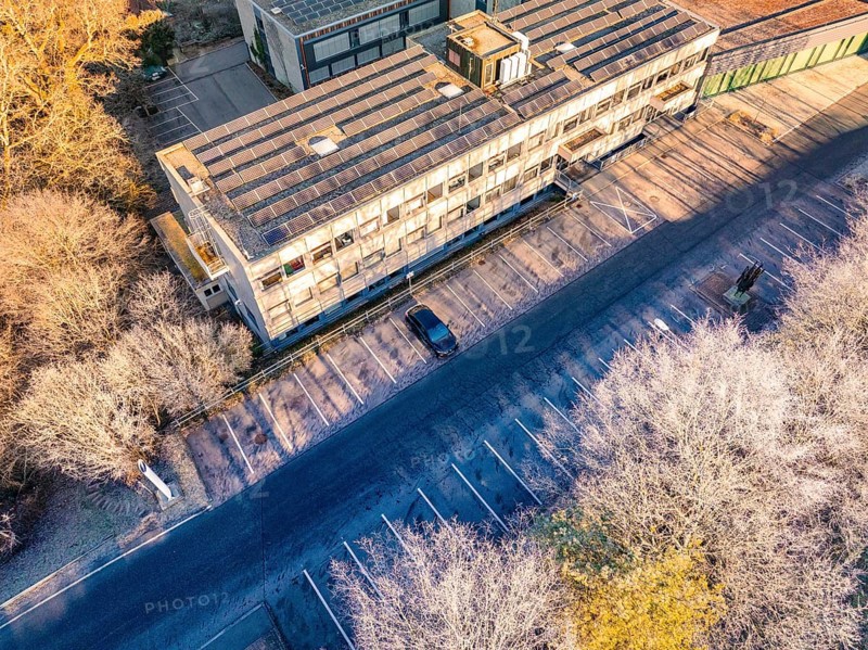 Building complex with empty parking spaces, surrounded by a winter tree landscape, MG4 electric car, deer e-car sharing, Calw, Germany