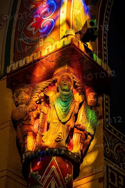 Issoire. Pillar (The Annunciation made to Mary) . The figures are illuminated by colorful light shining through a stained glass window inside Saint Austremoine Abbey, Puy de Dome, Auvergne Rhone Alpes, France