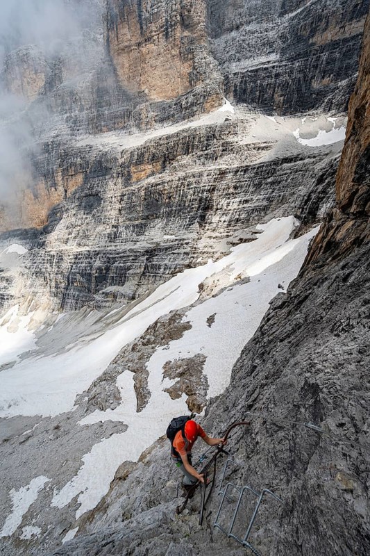 Mountaineer climbs a ladder in steep rocky terrain, Via Ferrata Oliva Detassis via ferrata, Brenta Mountains, Trentino, Italy