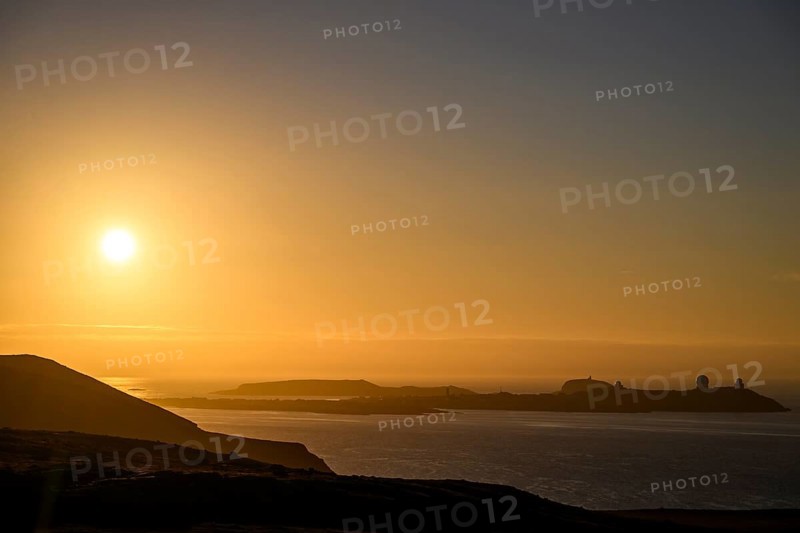 Midnight sun on Mount Domen in the background the city of Vardø, sea at sunset with golden sky and calm atmosphere, Kiberg, Finnmark, Norway