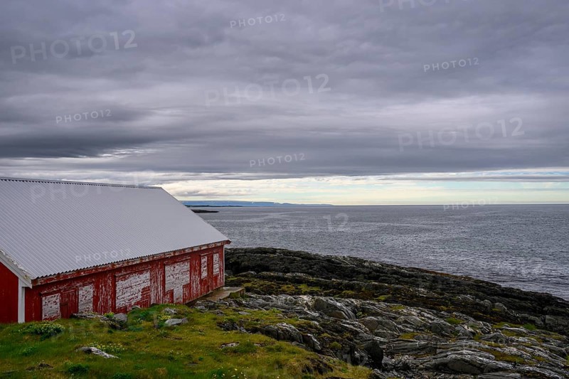 A red barn at Kjølnes Fyr, small windows and railings in a rural area, Berlevåg, Finnmark, Norway