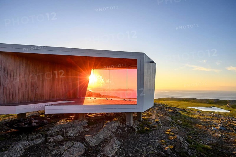 Modern building with glass wall in front of sunset on Mount Domen, sea view, nestled in rocky landscape, Kiberg, Finnmark, Norway