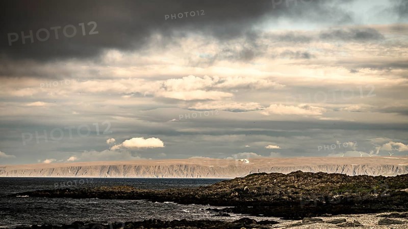 Atmospheric coastal landscape with cloudy sky over a vast sea on the coastal road in the north of the Varanger Peninsula, Berlevåg, Finnmark, Norway