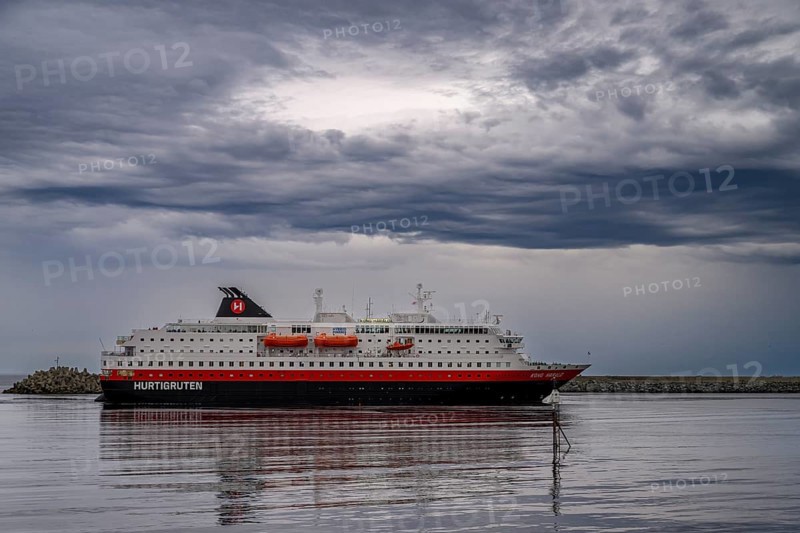 The Hurtigrouten Hurtigruten ship Kong Harald arrives at Berlevag harbour, on the horizon with a cloudy sky, Berlevåg, Finnmark, Norway