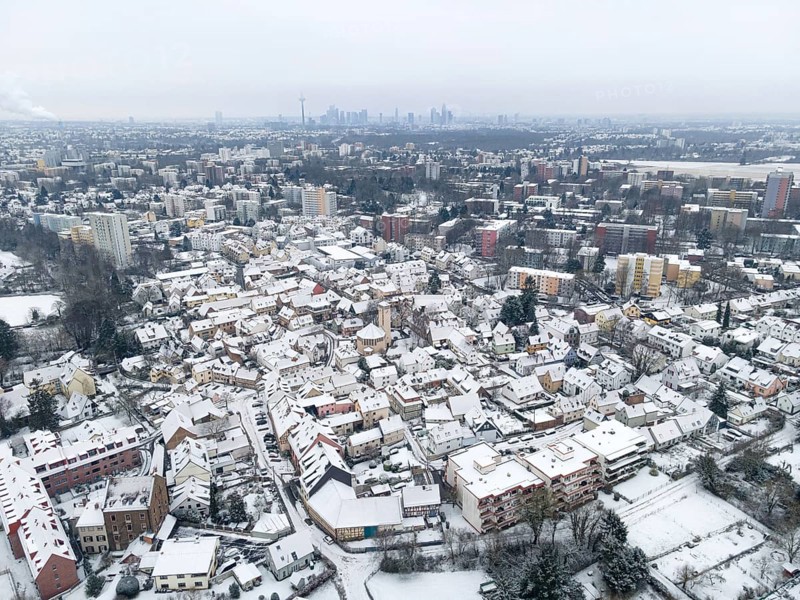 The Niederursel district of Frankfurt and the surrounding area are covered with snow. The towers of Frankfurt's banking skyline rise on the horizon, Niederursel, Frankfurt am Main, Hesse, Germany