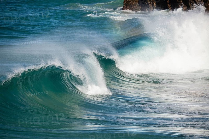 Waves crash against rocks at the mainland's easternmost point, creating rainbows in the ocean spray. Daylight, Byron Bay, New South Wales, Australia