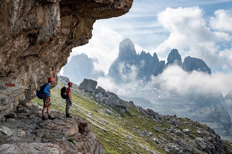 Two mountaineers on a path in front of a picturesque mountain landscape with rocky peaks, Via Ferrata SOSAT via ferrata, Cima Tosa summit in the back, Brenta Mountains, Trentino, Italy