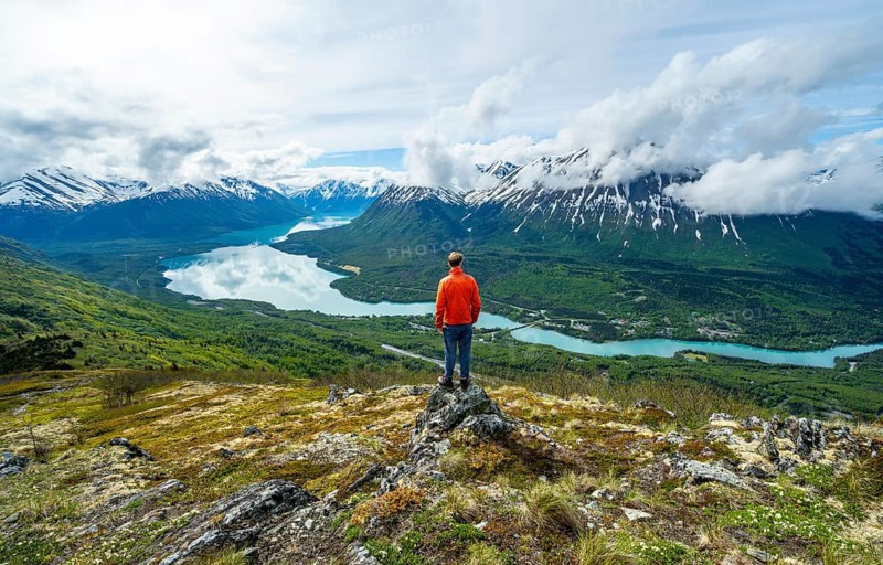 Climber enjoying the view, Slaughter Ridge Trail, view of snowy mountains and turquoise blue Kenai Lake, Cooper Landing, Kenai Peninsula, Alaska, USA