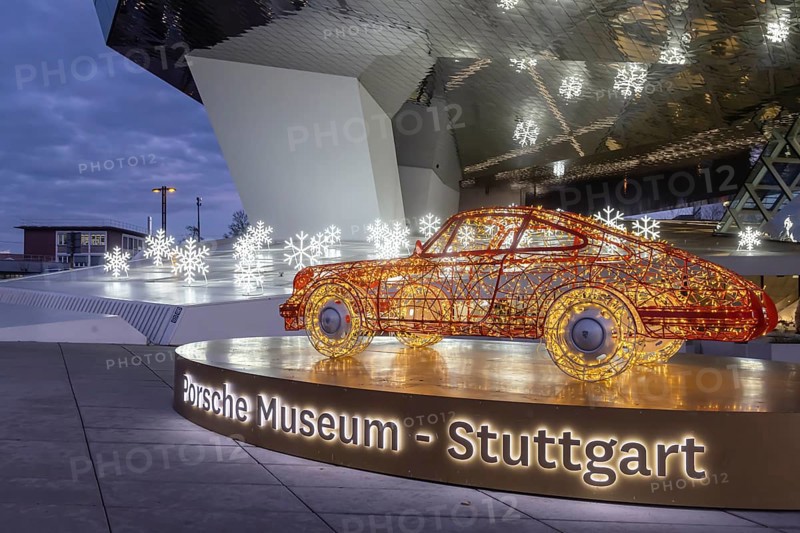 Highlights on Porscheplatz in Zuffenhausen. In front of the Porsche Museum and the car manufacturer's headquarters, a 911 sports car shines in Christmassy splendor. Stuttgart, Baden-Württemberg, Germany