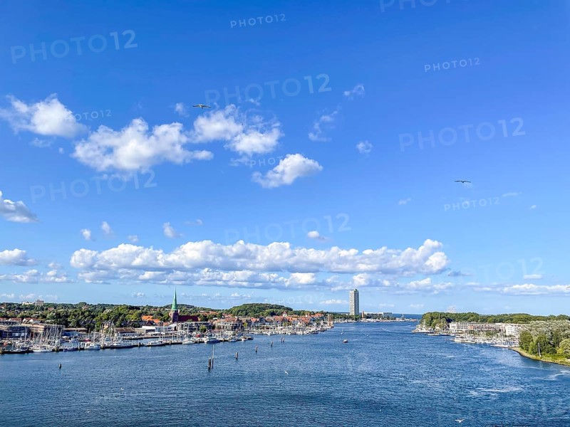 View over the Trave towards the mouth in the underground, the church of Travemünde and the Atlantic Hotel, with clouds and birds, Travemünde, Lübeck, Schleswig-Holstein, Germany