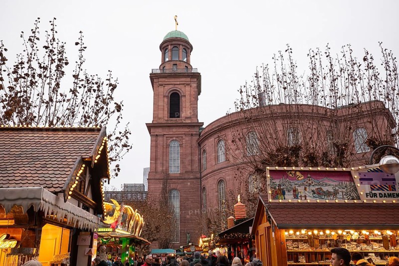 December 22, 2025, people strolling past festive wooden stalls at the Christmas market near St. Paul's Church, Frankfurt, Hesse, Germany