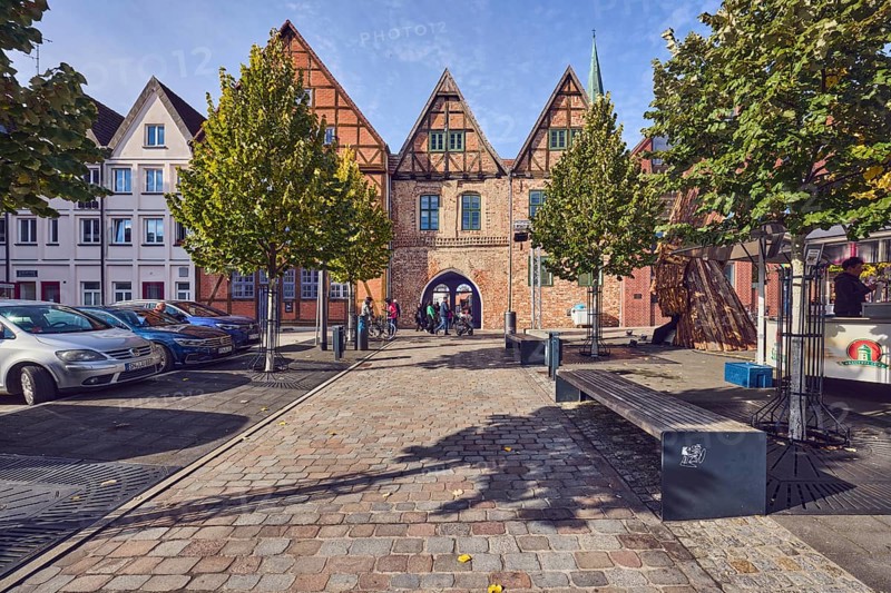 Row of houses, old town, half-timbered building, brick building material, residential building, passage arch, benches, parking lot with cars, trees, autumn leaves, cobblestone walkway, beer car, blue sky, cirrostratus clouds, slaughtermarket, Schwerin, state capital, district-free city, Mecklenburg-Western Pomerania, Germany