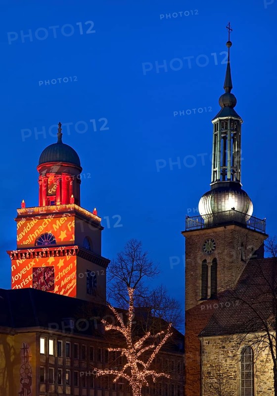 The Christmassy illuminated town hall tower and the illuminated church tower of St. John's Church in Witten, Ruhr area, North Rhine-Westphalia, Germany