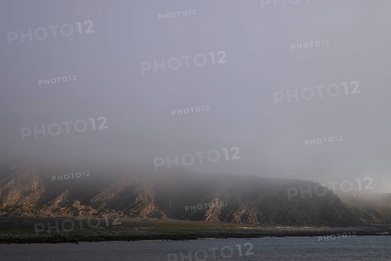 Misty coastal landscape with rocks creating a mystical and gloomy atmosphere, Båtsfjord, Finnmark, Norway