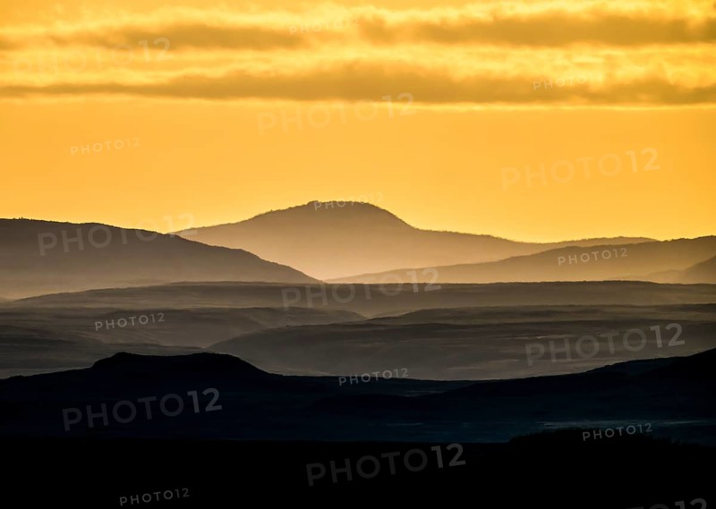 Silhouettes of mountains at sunset with yellow sky, near Vadsö, Finnmark, Norway