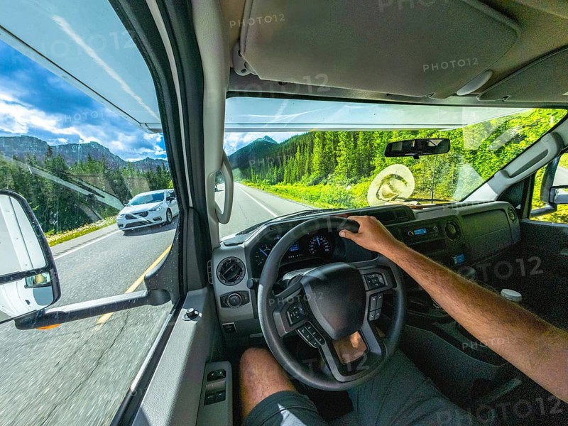 Pov driving a vehicle on the scenic icefields parkway in the canadian rockies with mountains and lush forests visible through the windshield on a sunny day