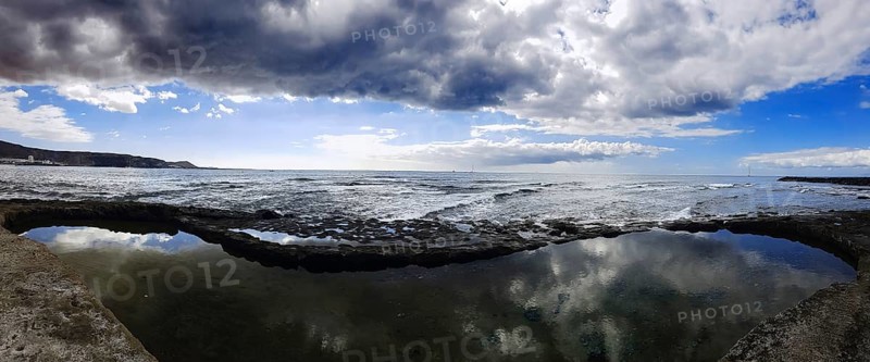 Broad view of a coastal landscape with cloud reflection in the water, Los Cristianos, Tenerife