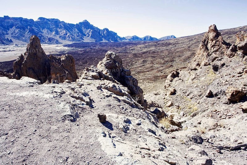 Rough volcanic landscape with rocky mountains in the background under clear sky, Pico del Teide National Park, La Orotava Tenerife