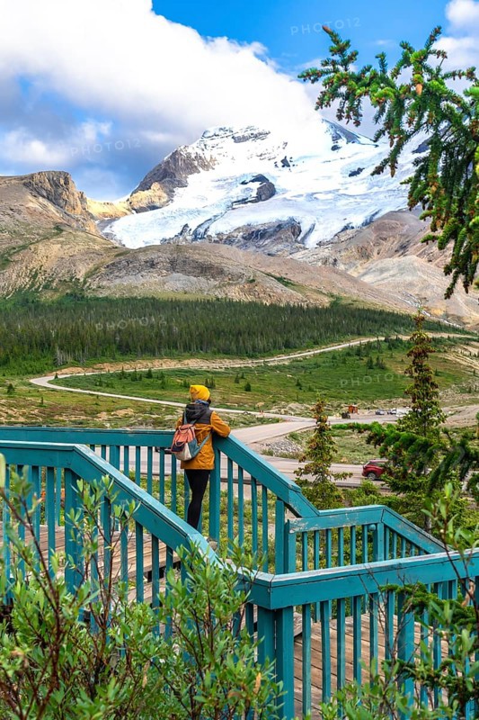 Tourist standing on a wooden stairway, admiring the stunning view of athabasca glacier in jasper national park, alberta, a favorite spot for nature lovers and adventurers