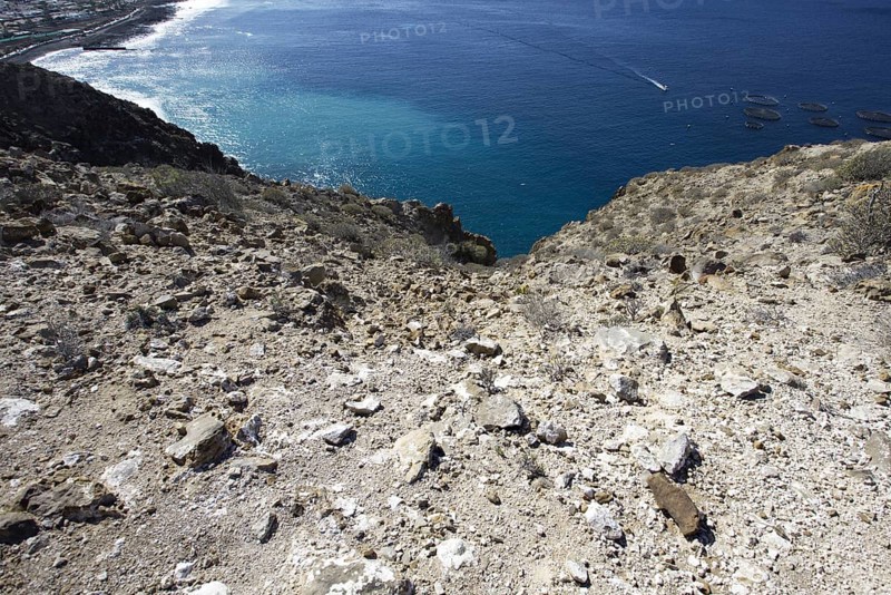 View of the deep blue sea from a rocky slope, with the coast running in the background, Los Cristianos Tenerife