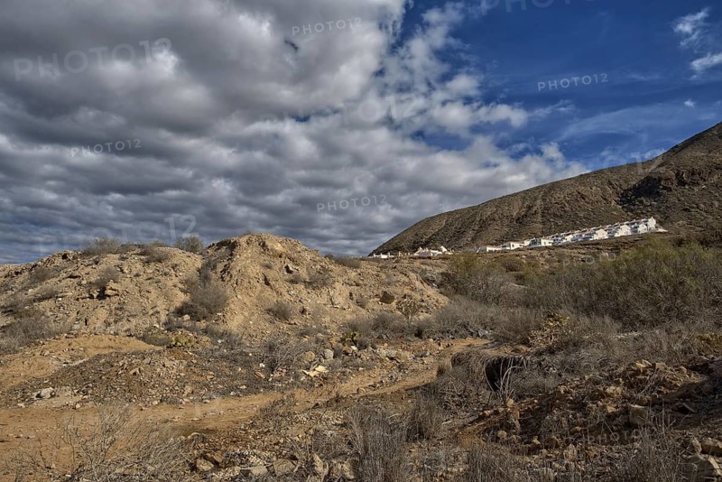 Rocky hills with cloudy sky and a settlement on the horizon, Los Cristianos Tenerife