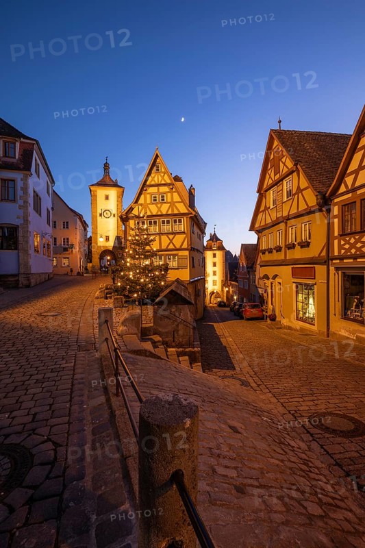 December 25, 2025: Christmastime at Plönlein — Rothenburg ob der Tauber, Bavaria, Germany. Festive Christmas tree and city lights at blue hour with moon in the sky