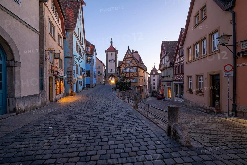 December 25, 2025: Christmastime at Plönlein — Rothenburg ob der Tauber, Bavaria, Germany. Festive Christmas tree and city lights at blue hour with moon in the sky