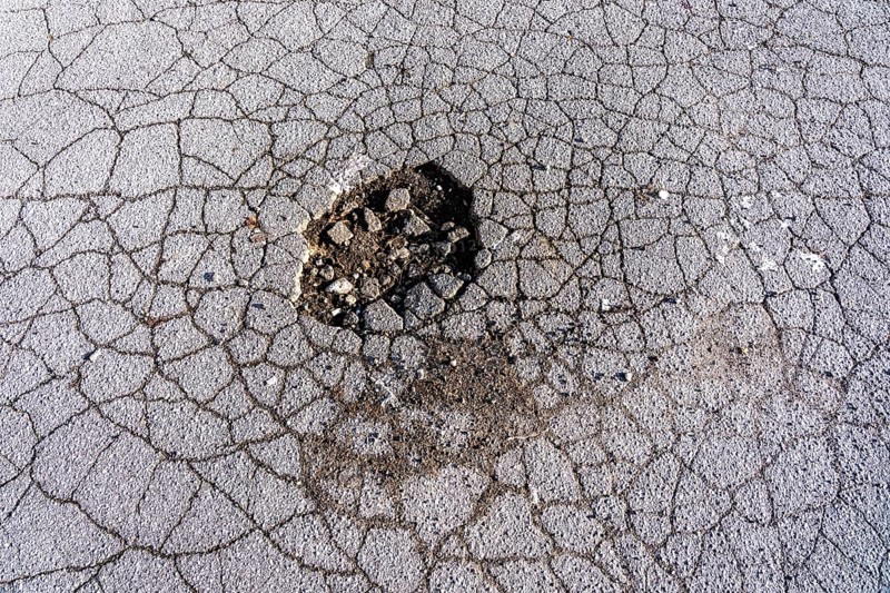 Pothole, asphalt surface, floor, with many small cracks, roadway, parking lot
