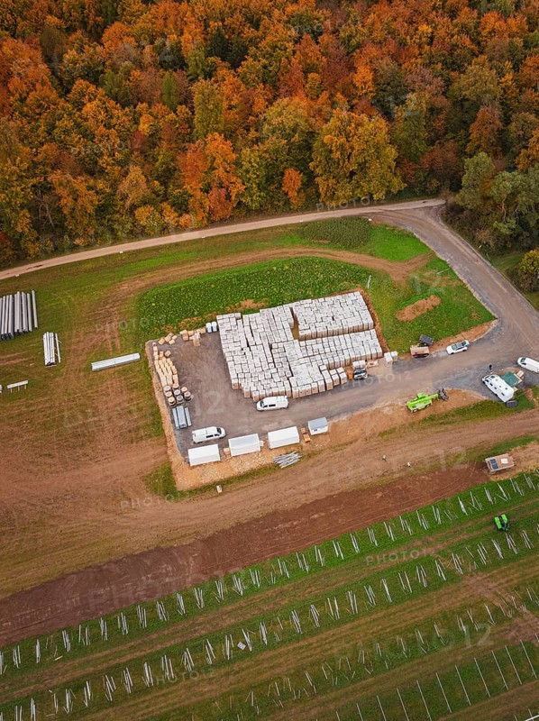 Autumn aerial view of a building materials warehouse with surrounding fields and an adjacent road, Energiewende, construction of PV open space, Baden-Württemberg, Germany