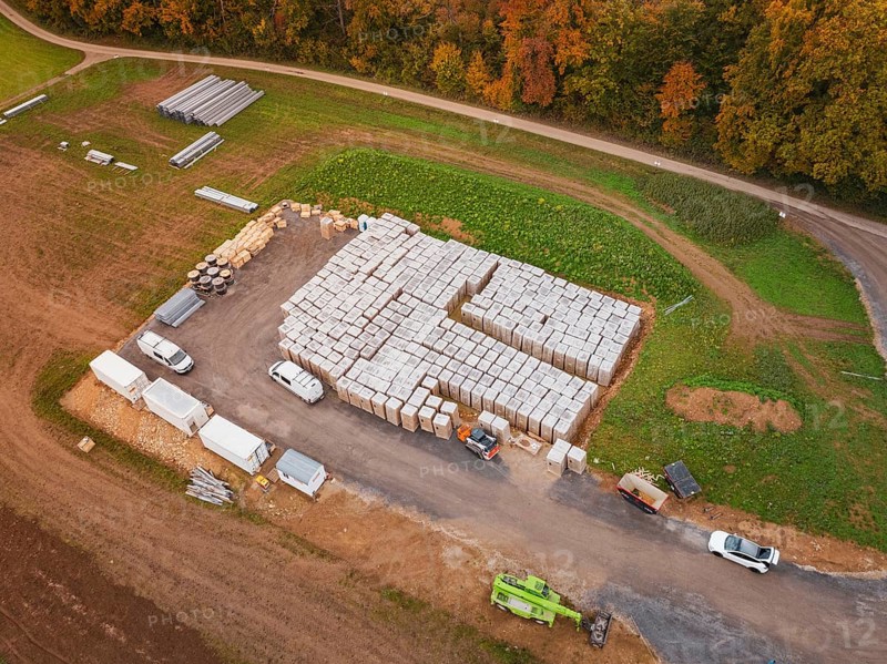 Warehouse with building materials and vehicles, surrounded by fields and an asphalted road, energy transition, construction of PV open space, Baden-Württemberg, Germany