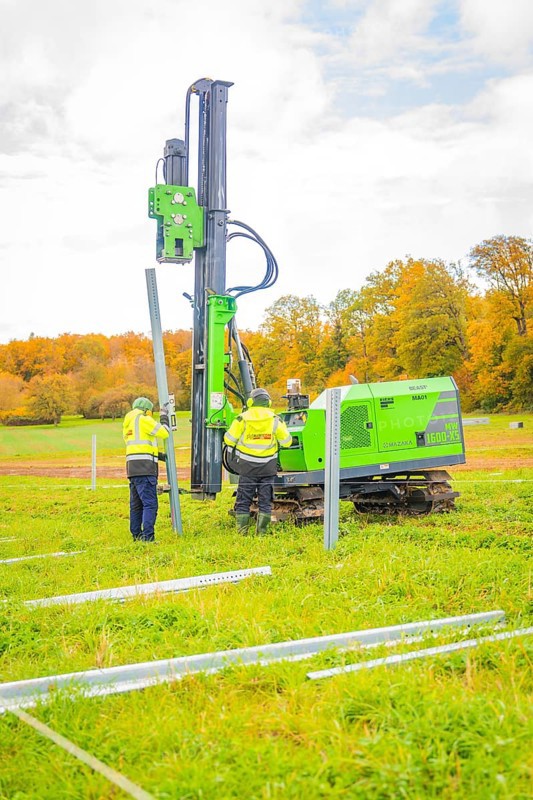 Two workers set up posts in a meadow with a drilling rig, Energiewende, construction of PV open space, Baden-Württemberg, Germany