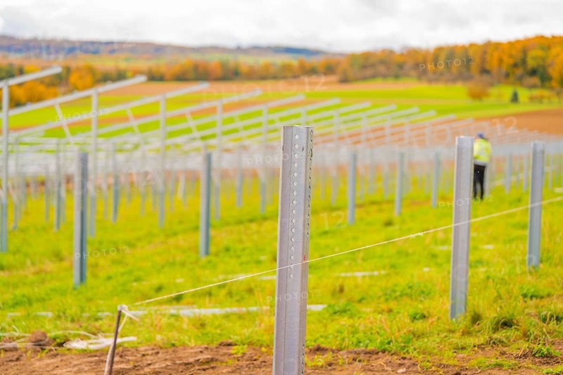 Metal poles along a field under cloudy sky with autumn landscape in the background, Energiewende, construction of PV open space, Baden-Württemberg, Germany