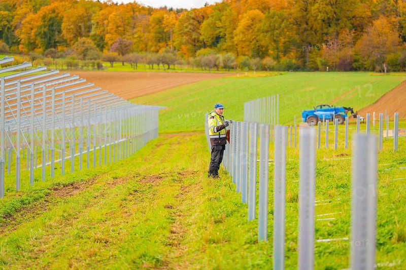 A worker installs poles in a field on a clear autumn day, Energiewende, construction of PV open space, Baden-Württemberg, Germany