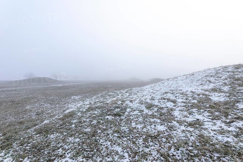 Mystical Celtic burial mounds in winter fog near Erkenbrechtsweiler. Snowy historic burial sites on Heidengraben in the Swabian Jura in an atmospheric winter atmosphere