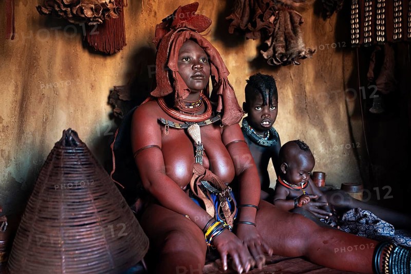 Himba woman sitting with baby, Himba perfume, scented smoke from burning plants, Himba village, Kaokoveld, Kunene, Namibia