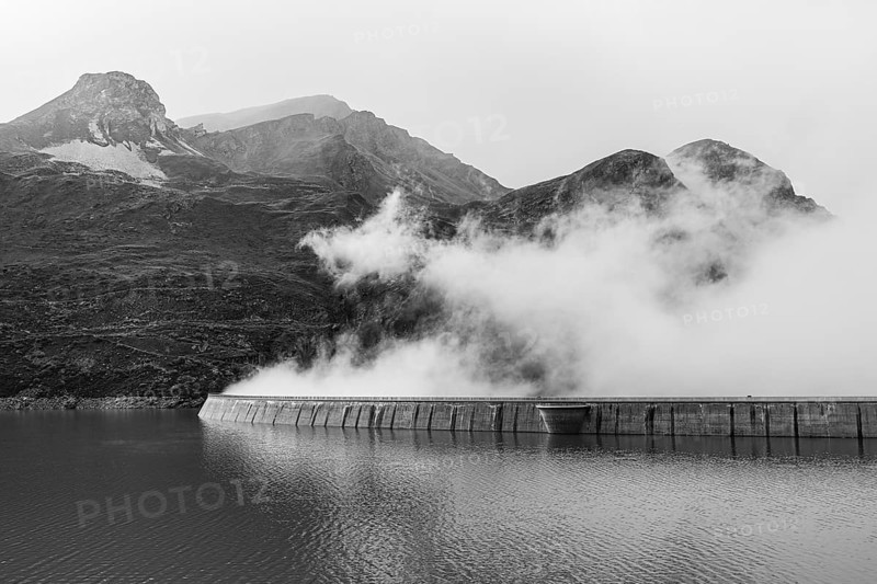 Fog rises over the dam of the Lac de Moiry reservoir, black and white photo, Val d'Anniviers, Valais Alps, Canton of Valais, Switzerland
