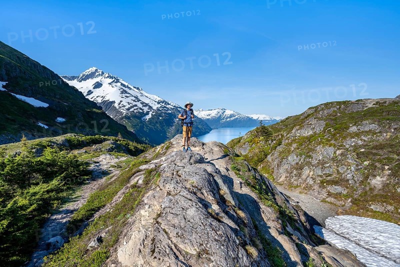 Hikers on Portage Pass, snow-covered mountains and Fjord Passage Canal, near Whittier, Alaska, USA