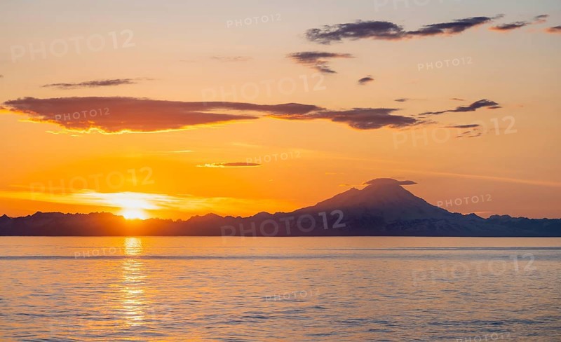 View of Cook Inlet on white mountain peaks of Mount Redoubt at sunset, picturesque golden light of the midnight sun, mountains of the Aleutian Range, Anchor Point, Anchor River State Recreation Area, Alaska, USA