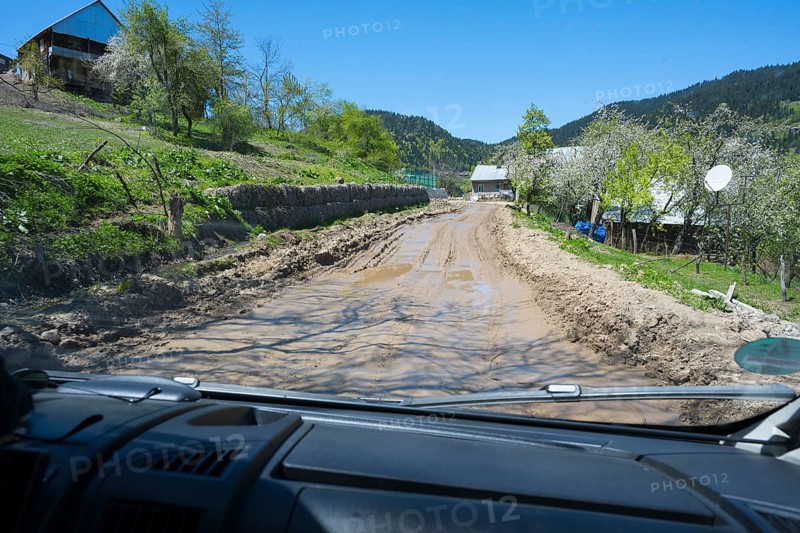 A muddy country road is viewed from a driving perspective through a car window, campers on a four-wheel drive track on the way to the Goderdzi Pass, Ajara region, Adjara, Autonomous Republic, Georgia