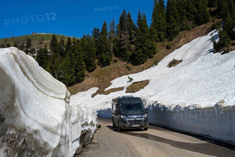 A van drives through a snowy road gorge surrounded by conifers, camper near Goderdzi on the way to the Goderdzi Pass, Ajara region, Adjara, autonomous republic, Georgia