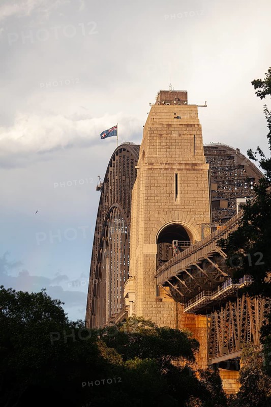Side view of Sydney Harbour Bridge at sunset with the Australian flag