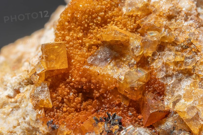 Shiny crystals of blue and orange color can be seen in this mineral formation. They are sparkling and show interesting textures in a natural setting