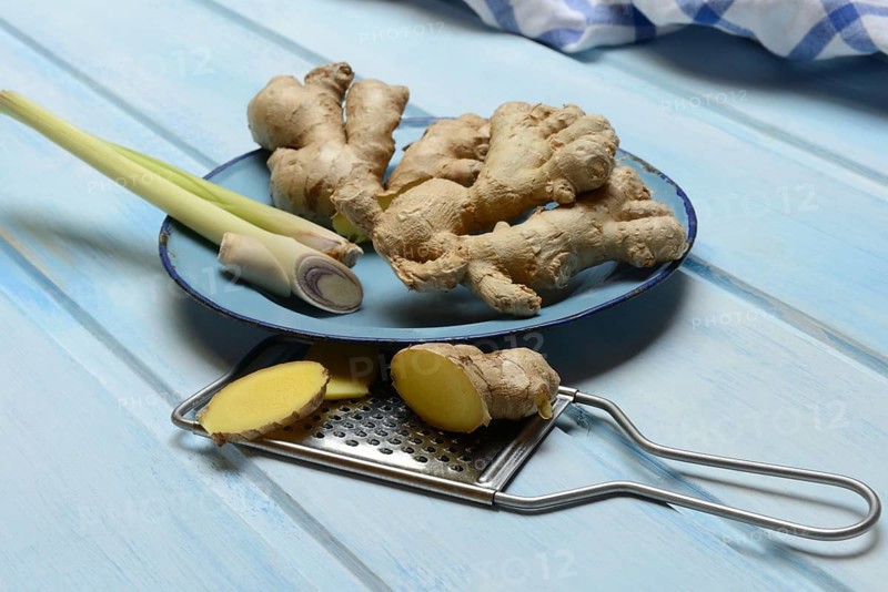 Ginger tubers and lemongrass on plate, grater with ginger pieces